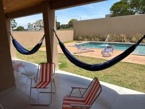 un porche avec deux chaises et un hamac et une piscine dans l'établissement Riviera Santa Cristina XIII 05 suítes, à Palmeiras 106 autres photos