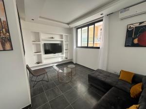 a living room with a couch and a tv at Mermoz Keur Gorgui Penthouse Modern Cosy Wifi HD DPL5B in Grand Dakar