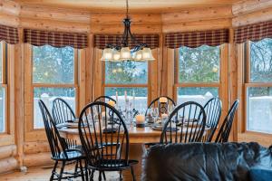 ein Esszimmer mit Tisch und Stühlen und Fenstern in der Unterkunft Fiddler Lake Resort Chalet 80 Deer with pool in Mille-Isles + 19 Fotos