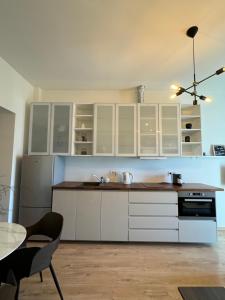 Una cocina con gabinetes blancos y una mesa. en Sun Shine apartment, en Liepāja