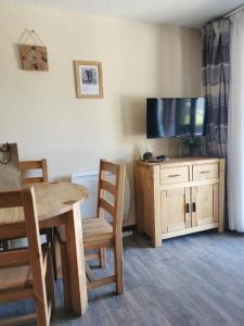 a dining room with a table and a television on a cabinet at Le Creux de l'Ours - au pied des pistes - animaux acceptés in Méribel