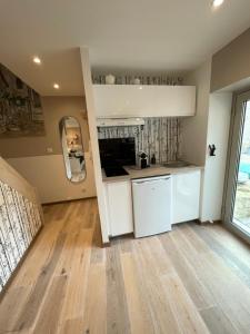 a kitchen with white cabinets and a wooden floor at Le Passage Secret in Fleury-en-Bière +12 photos