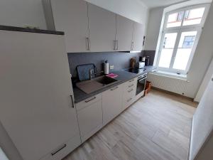 a kitchen with white cabinets and a sink and a window at Bummis exklusive Ferienwohnung in Güstrow +4 photos