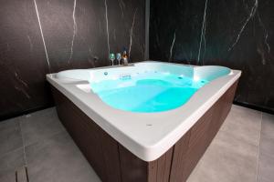 a bathroom with a tub with blue water in it at חוויה בכיכר גולד in Netanya +17 photos