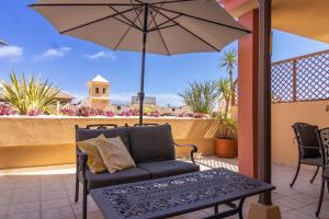 a patio with a couch and an umbrella at Terrazas del Duque II Hideaway in Adeje
