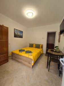 a bedroom with a bed with yellow sheets and a table at Къща за гости Кралимаркови Guest house Kralimarkovi in Devin