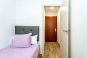 a bedroom with a bed with purple sheets and a door at Apartamento elegante villa verde 1B in Villaverde