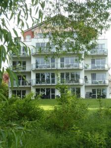 een groot wit appartementencomplex met balkons en bomen bij Große FeWo-Suite "Nordstern" in direkter Seelage, mit Kanu in Ascheberg