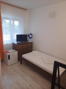 a bedroom with a bed and a dresser and a window at Vila Alba Brasov in Braşov