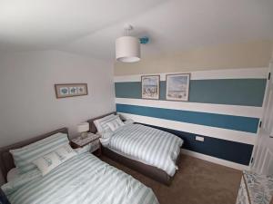 two beds in a room with blue and white stripes at 8 Guests Large cottage Hotub in Hornsea