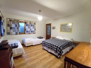 a room with two beds and a table at Hospedagem Maria de Liu in Palmeiras