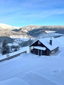 uma cabana de madeira na neve com montanhas ao fundo em Bílá Labuť Pec em Pec pod Sněžkou