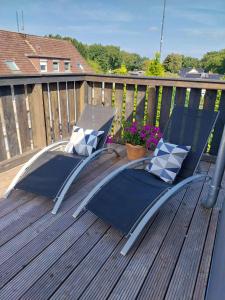 two chairs on a deck with a table and flowers at Ferienwohnung Schnelzer in Sahlenburg