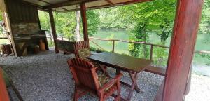 a porch with a table and chairs and a view of a river at Kucerak na Drini in Bajina Bašta