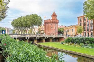 un pont sur une rivière à côté d'un bâtiment dans l'établissement Les suites du castillet, à Perpignan