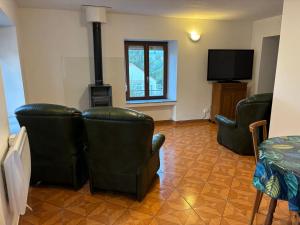 a living room with leather chairs and a flat screen tv at proche de la source in Ouhans