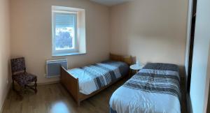 a bedroom with a bed and a chair and a window at proche de la source in Ouhans
