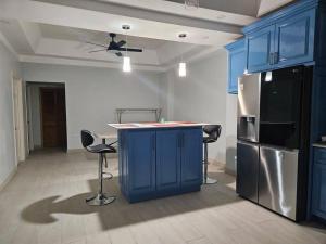 a kitchen with blue cabinets and a kitchen island with chairs at City Scape Serenity Kingston in Tunbridge
