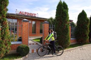 uma mulher de pé com uma bicicleta em frente a um edifício em Alpinist Hotel em Bishkek