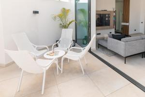 sala de estar con sillas blancas y sofá en Bungalow SIENA Center Playa del Inglés, en Maspalomas