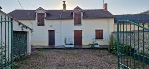 a white house with brown doors and a gate at Belle maison a Brizay in Brizay
