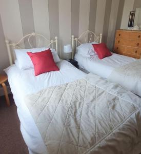 2 bedden met rode kussens in een slaapkamer bij Spaside Apartment in Scarborough