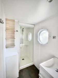 a white bathroom with a shower and a sink at AirCon Deluxe Mobilhome near Europapark in Boofzheim