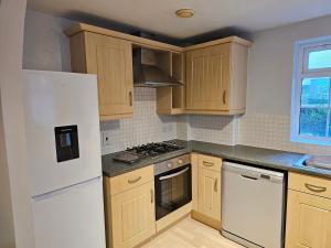 Una cocina con gabinetes de madera y un refrigerador blanco. en 2 bedroom spacious flat, en Gloucester