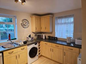 cocina con armarios de madera, lavadora y secadora en 2 bedroom spacious flat, en Gloucester