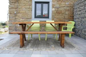 una mesa de picnic de madera y sillas en un patio en Vakantieboerderij Ferme Le Bleuet, en Ohey