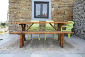 a wooden picnic table and chairs on a patio at Vakantieboerderij Ferme Le Bleuet in Ohey