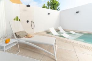Una silla blanca sentada junto a una piscina. en Bungalow SIENA Center Playa del Inglés, en Maspalomas