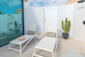 Una habitación con dos sillas blancas y un cactus. en Bungalow SIENA Center Playa del Inglés, en Maspalomas