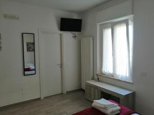 a white room with a window and a bed and a mirror at Angelana camere in Santa Maria degli Angeli