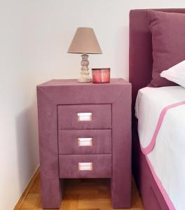 a purple nightstand with a lamp on it next to a bed at Luča apartman in Podgorica