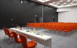 una sala de conferencias con mesas blancas y sillas naranjas en Demidov Plaza, en Nizhni Taguil