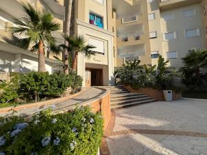 a building with a courtyard with palm trees and stairs at Outstanding Flat with pool and near the beach in Sahline