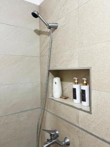 a shower with three bottles of soap on a shelf at B2 Apartment in Tirana +30 photos