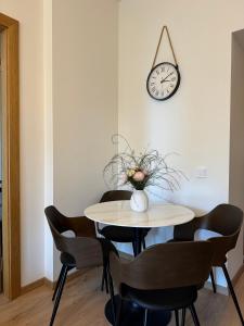 Una mesa de comedor con sillas y un reloj en la pared. en Sun Shine apartment, en Liepāja