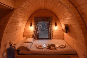 a bed in a wooden room with a window at RAZBIBRIGA - Riverside Camping Pod by IGLENA in Kupres