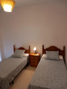 a bedroom with two beds and a lamp on a night stand at Apartamentos Lucero de Europa in Carmona
