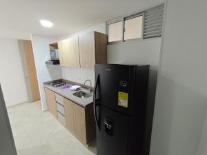 a kitchen with a black refrigerator and a sink at Apartamento Portal 18 in San Alonso