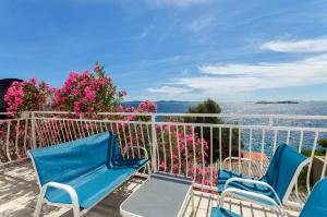 a balcony with blue chairs and pink flowers at Apartment Zamalin SeaView in Tribunj