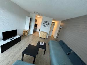 a living room with a couch and a clock on the wall at Studio chaleureux et lumineux in Orcières