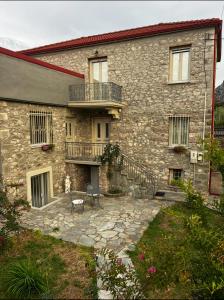 StoneVillaMouzaki Luxury Mansion في موزاكيون: مبنى حجري مع شرفة وفناء