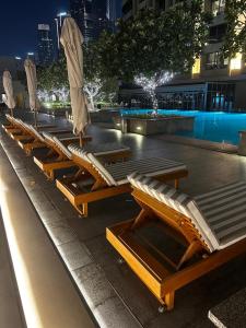 Una fila de tumbonas junto a una piscina por la noche en Fashion Avenue Dubai Mall Burj Khalifa View Residence- Formerly Address Dubai Mall, en Dubái