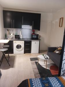 a kitchen and living room with a couch and a table at Studio rez-de-chaussée in Bougival