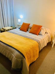 a bedroom with a large bed with orange pillows at Departamento Central, con estacionamiento gratuito in Talca