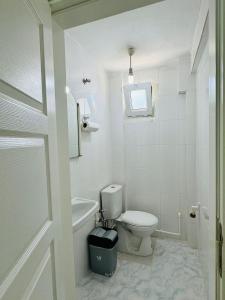 a white bathroom with a toilet and a bath tub at Troya Garden Villa in Canakkale