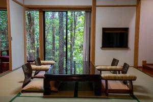 屋久島にある天然温泉と縄文の宿「まんてん」のダイニングルーム(ガラスのテーブル、椅子、窓付)